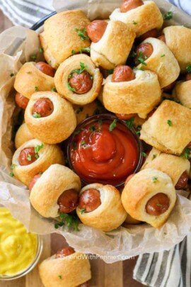cooked Pigs in a Blanket on a plate with ketchup and mustard dips