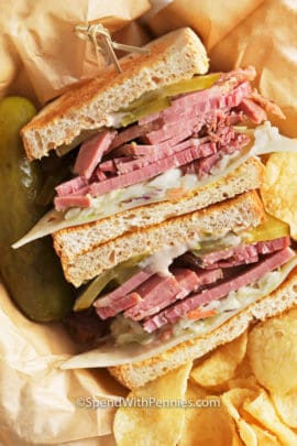 Corned Beef Sandwich on parchment paper with chips on the side