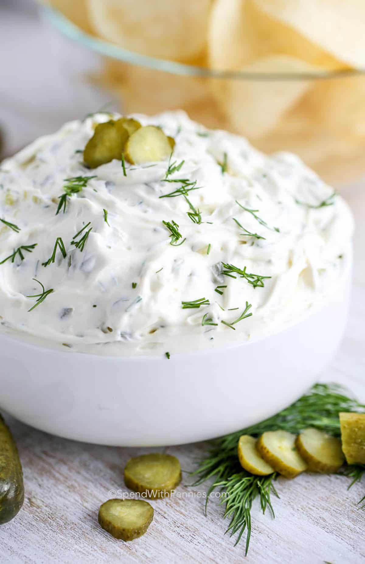 dill pickle dip in a bowl with fresh dill and sliced pickles