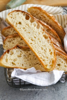 sliced artisan bread in a basket with kitchen towels