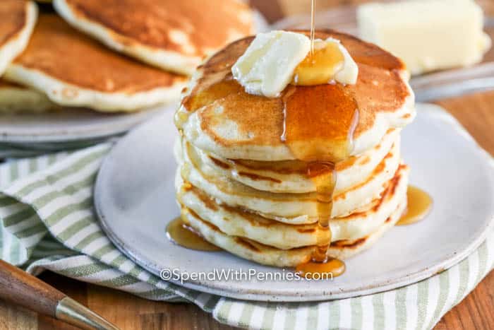 Stack of pancakes on a plate with butter and syrup