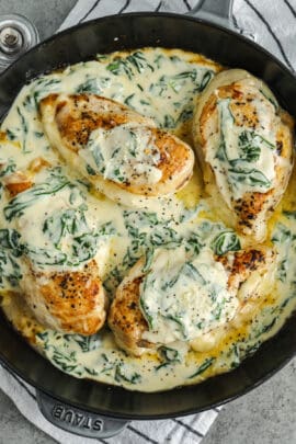 cooked Spinach Stuffed Chicken Breasts with sauce in a pan
