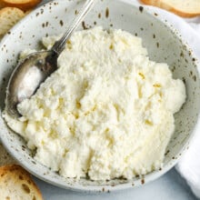 a bowl of homemade ricotta cheese next to crostini