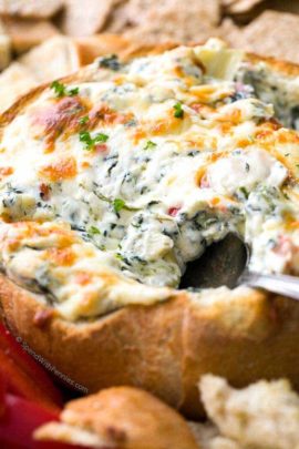 taking a spoonful of Hot Spinach and Artichoke Dip in a bread bowl