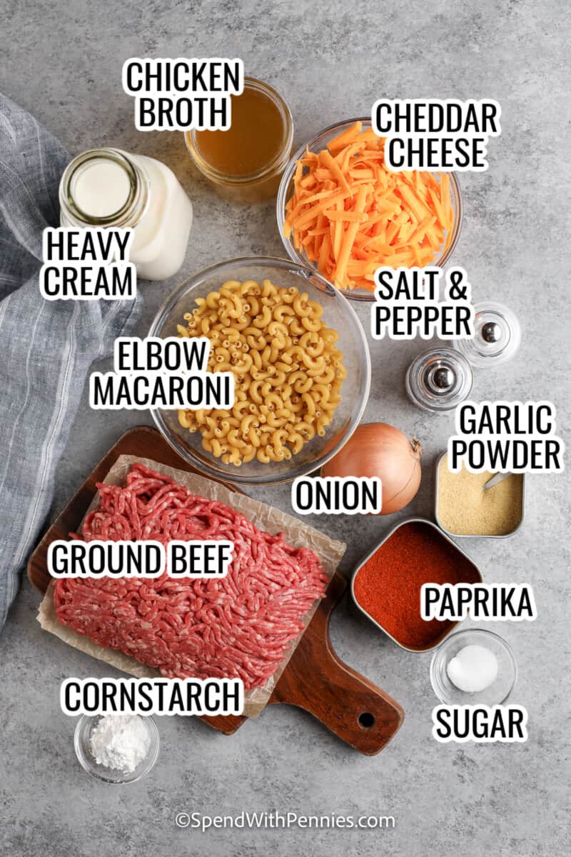 ingredients assembled to make homemade one pot cheeseburger macaroni, including ground beef, cheddar cheese, heavy cream, chicken broth, onion, macaroni, garlic powder, cornstarch, and sugar
