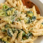 broccoli pasta on a white plate with a wooden spoon