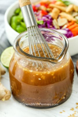 Sesame Ginger Dressing in a jar with a whisk and salad in the background
