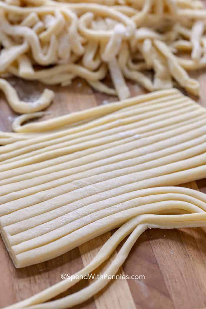 Strips of Homemade Egg Noodles on a wooden cutting board