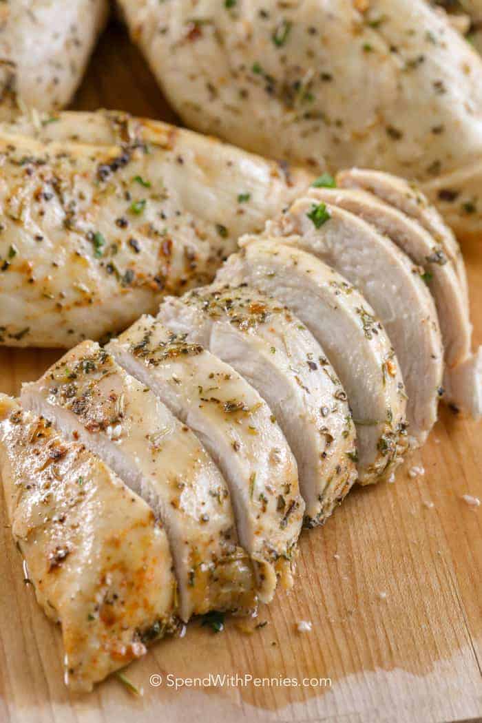 Baked Chicken sliced diagonally for serving on a wood board
