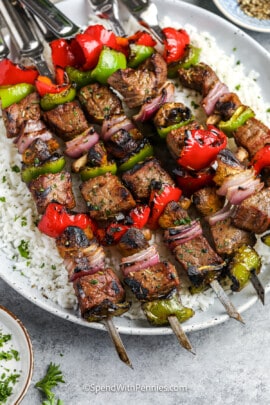 steak kabobs on a plate of rice