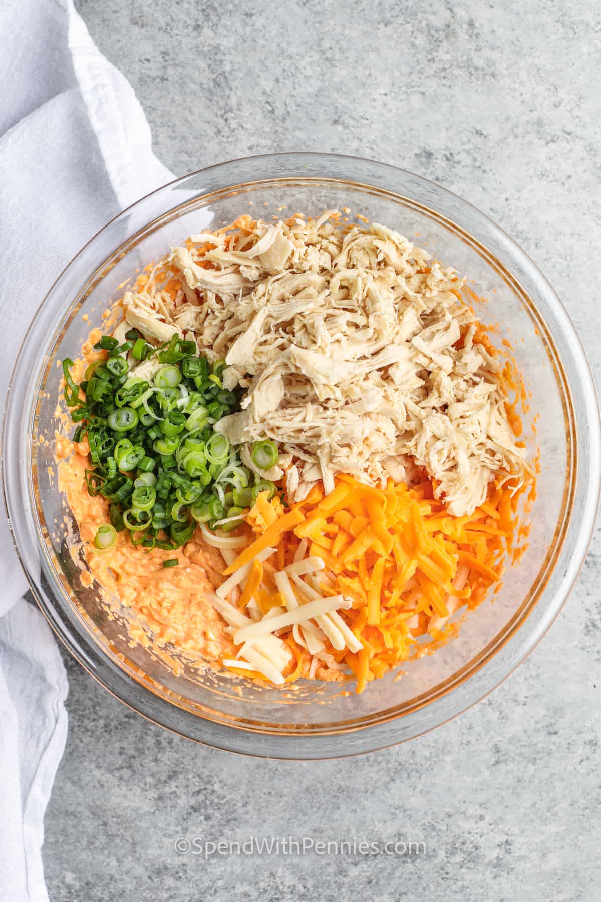 adding cheese ,green onions and chicken to bowl to make The Best Buffalo Chicken Dip