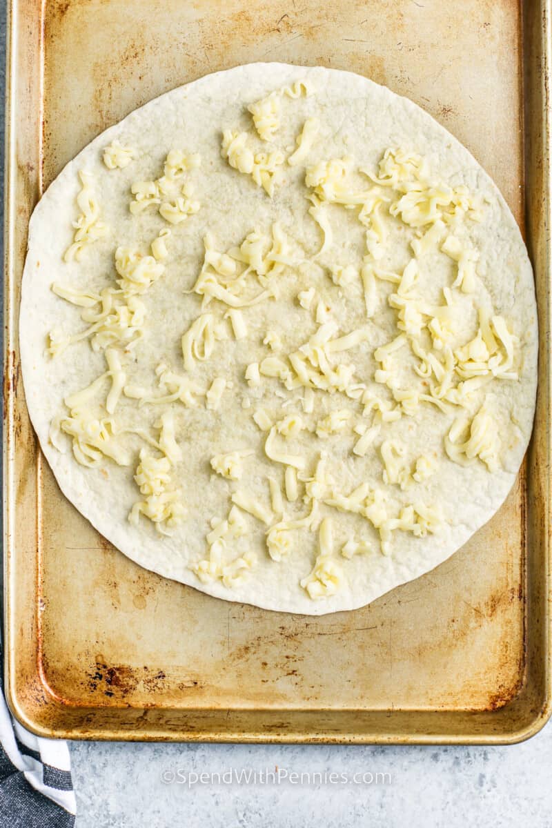 adding cheese to tortilla to make a Tortilla Pizza