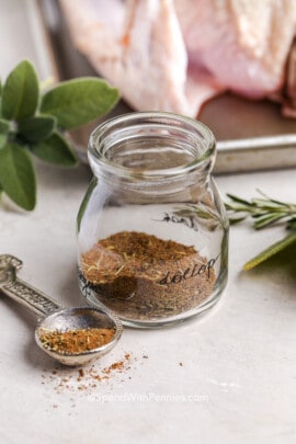 a jar of homemade turkey seasoning with a herbs in the background